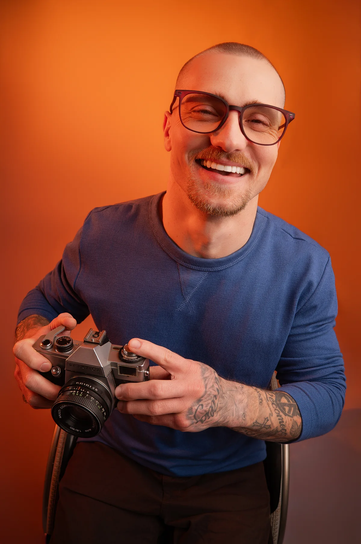 Homem sorrindo de óculos segurando uma câmera